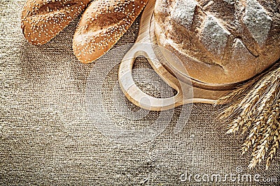 Carving board bread baguette wheat ears on sacking background Stock Photo