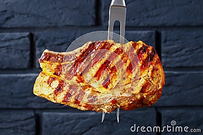 Carving fork with speared grilled pork chop Stock Photo