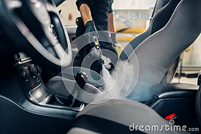 Carwash, worker cleans seats with steam cleaner Stock Photo