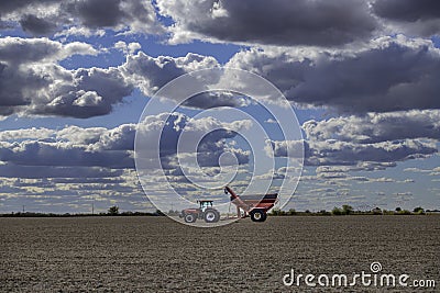 Case IH tractor and an Unverferth grain cart rest in a completely harvested field Editorial Stock Photo