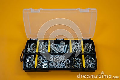 Case organizer with screws, nuts and washers on a yellow background. Stock Photo
