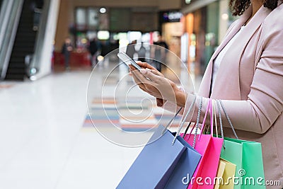 Cashback Bonus. Woman With Shopper Bags Using Smartphone In Mall After Shopping Stock Photo