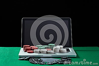 Casino chips and cards on keyboard notebook at green table. Stock Photo