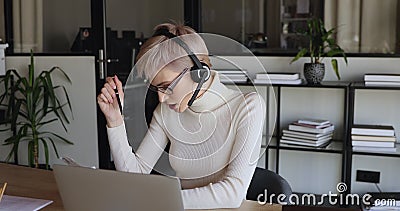 Casque de port femelle de sourire d'employé de bureau communiquant par l'appel vidéo banque de vidéos Casque de port femelle de sourire d'employé de bureau communiquant par l'appel vidéo banque de vidéos