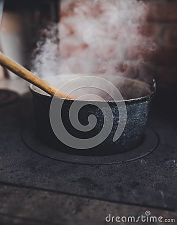 Cast iron cauldron boiling a goulash stew over a wood burning stove made from red bricks in the backyard of a rural house in Stock Photo