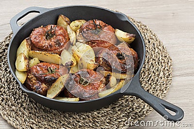 Cast iron pan with tomatoes with rice and baked potatoes Stock Photo