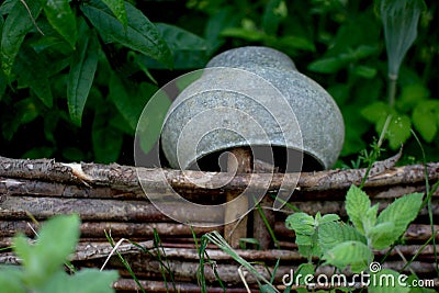 Cast iron pot on a vine fence surrounded by greenery Stock Photo