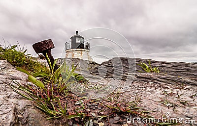 An anchor stands out in the dramatic rocky coastline at Castle Hill Lighthouse in Newport, Rhode Island, under a stormy sky Stock Photo