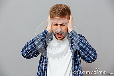 Casual bearded man covering his ears and shouting Stock Photo