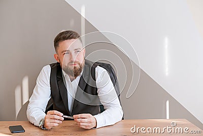 Casual business man bearded, sitting at table with pen in his hand, thinking Stock Photo