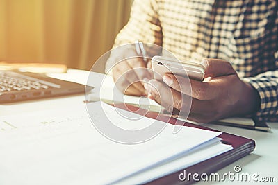 Casual business man using mobile smart phone working, taking note, schedule on paper notebook, reading e book application. E Stock Photo