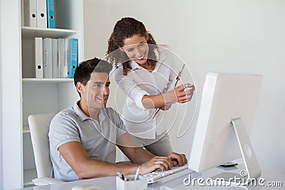 Casual business team looking at computer together at desk Stock Photo