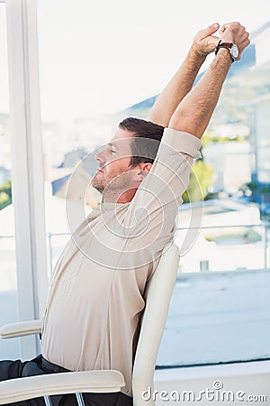 Casual businessman stretching in swivel chair Stock Photo