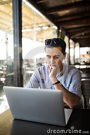 Casual businessman working with laptop in cafe young asian entrepreneur thinking about project. Freelance work Stock Photo