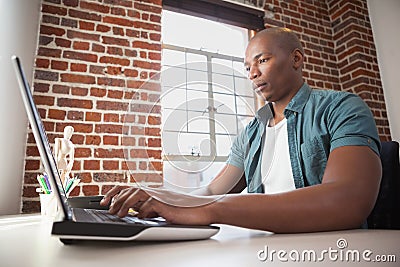 Casual businessman working on laptop at desk Stock Photo
