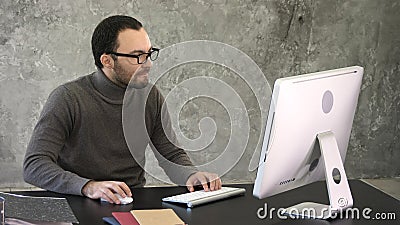 Casual businessman working in office, sitting at desk, typing on keyboard, looking at computer screen. Stock Photo