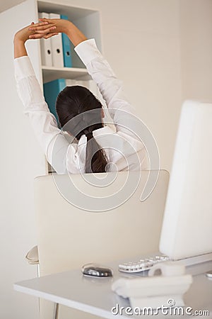 Casual businesswoman stretching at her desk Stock Photo