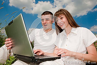 Casual happy couple on a laptop computer outdoors Stock Photo