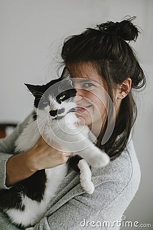 Casual happy woman hugging cute cat in stylish modern room. Sweet authentic home moments Stock Photo