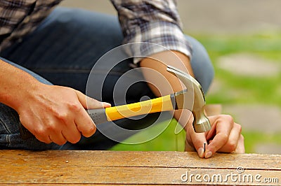 Casual man hammering nail in plank at home Stock Photo