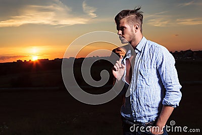 Casual man looks to his side with sunset behind Stock Photo