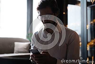 Casual man relaxed using smart phone, young man browsing on smart phone in cafe interior. Stock Photo