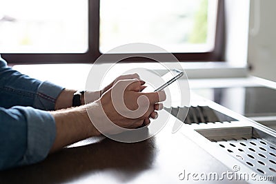 Casual man using smartphone at home kitchen, young man browsing on smart phone in interior, e-business. Stock Photo