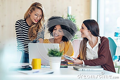 Casual multiethnic business women working with laptops while talking of they new projects together in coworking place Stock Photo