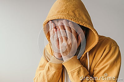 Casual sad man in yellow hoodie is crying in emotional breakdown situation Stock Photo