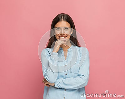 Casual woman touching her chin, smiling and sending positive vibes Stock Photo