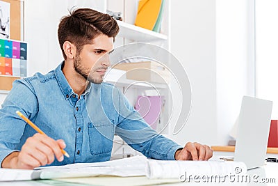 Casual young businessman looking at laptop and working with documents Stock Photo