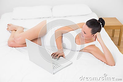 Casual young woman using laptop in bed Stock Photo