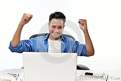 Startup business man raising his hands feeling happy for achieving work while using laptop Stock Photo