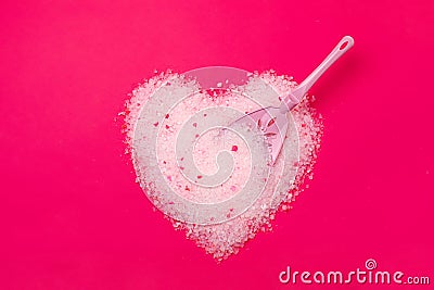 Cat litter, heart shaped bright pink background with a spatula for cleaning poop. Concept for labels, packaging advertising of the Stock Photo