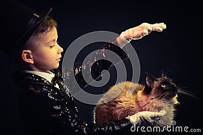 Cat and Magician kid illusionist boy in hat. trick mystery black background Stock Photo