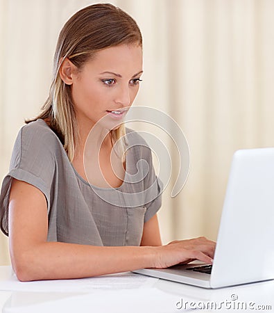 Catching up on a few emails. A young woman sitting inside and working on her laptop. Stock Photo