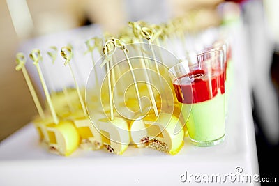 Catering, delicious new dessert canapes with yellow mango on a skewer and red-green mousse dessert in a glass Stock Photo