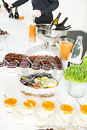 Catering Desserts on Buffet Table with Man Serving Red Wine in the Background Stock Photo