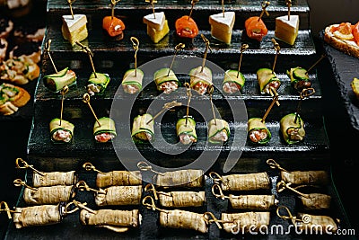 Catering food. Canapes with salmon, rolls with cheese and cucumber on skewers. Stock Photo