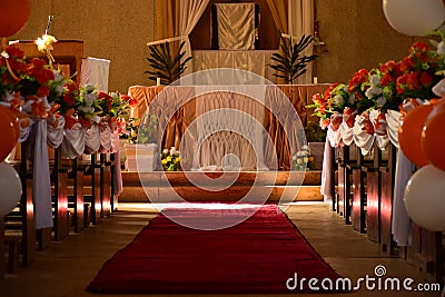 Church decoration on wedding day with flowers and ballons and a red carpet in orange theme and the sunrays falling through Stock Photo