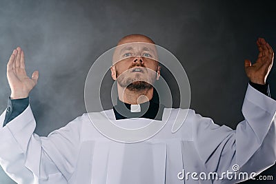 Catholic priest in white surplice and black shirt with cleric collar praying Stock Photo