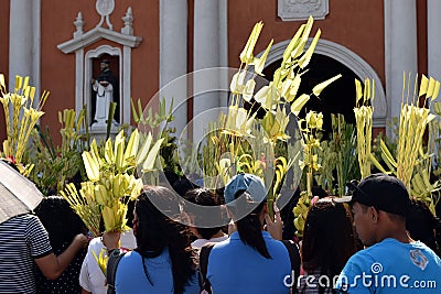 Catholics waving coconut palm leaves in celebrating Palm Sunday before Easter, Church tower background, The feast commemorates Jes Editorial Stock Photo