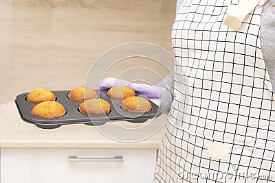 Caucasain woman holding tray with freshly made cupcakes or maffins at the kitchen Stock Photo