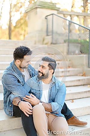 Caucasian american gays sitting on concrete stairs and hugging. Stock Photo