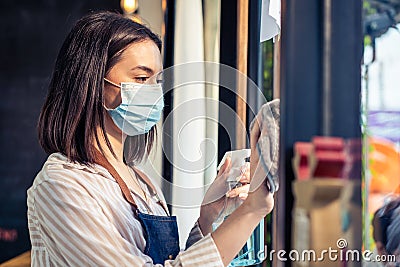 Caucasian attractive waitress wear protective mask to prevent from Covid-19 pandemic at cafe. Young business owner girl barista in Stock Photo