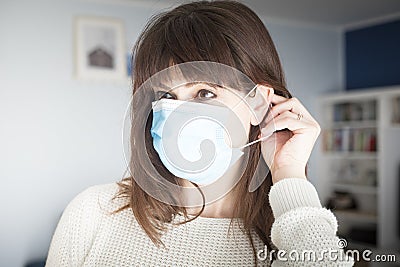 Caucasian attractive woman portrait putting on a blue face mask during covid-19 pandemic Stock Photo