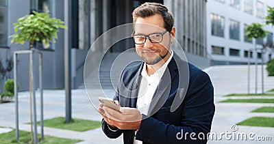 Caucasian attractive young stylish man tapping or scrolling on tablet device in town at street. Handsome male texting Stock Photo