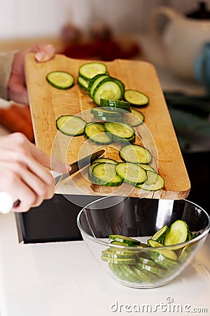 Caucasian attractive young woman is cutting cucumb Stock Photo