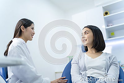 Caucasian beautiful girl talks and consult with Asian female dentist for cavities and gum disease in tooth care program of dental Stock Photo