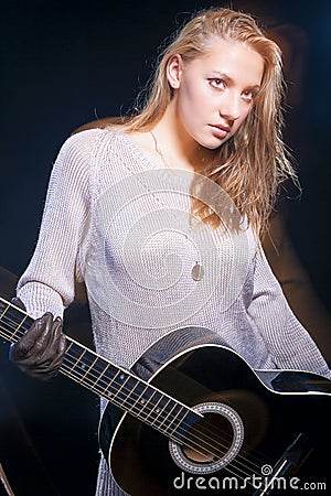 Caucasian Blond Female Posing with Guitar Against Black. Halogen and Flash Light Used Stock Photo